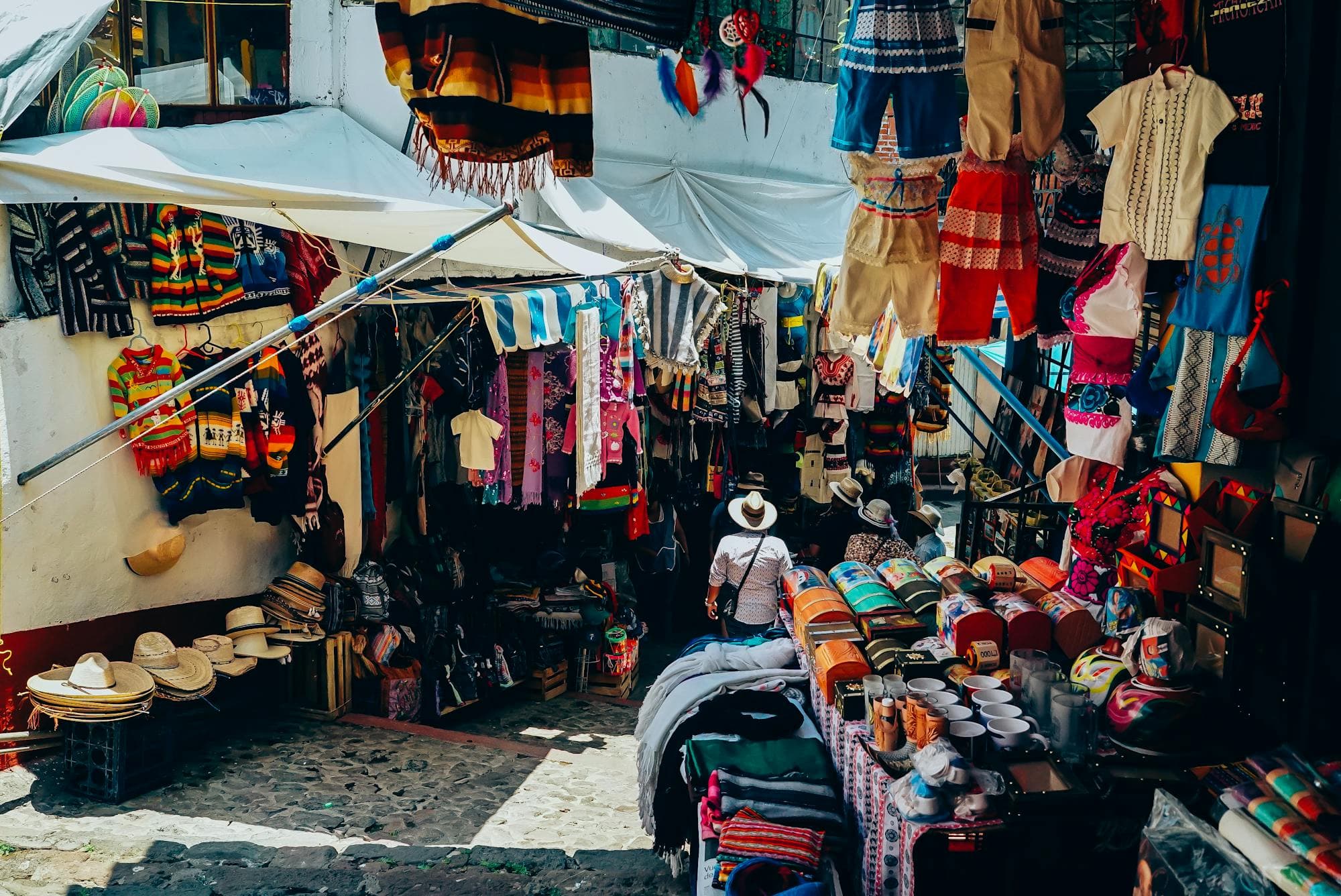 An outdoor market stall with traditional clothing and crafts
